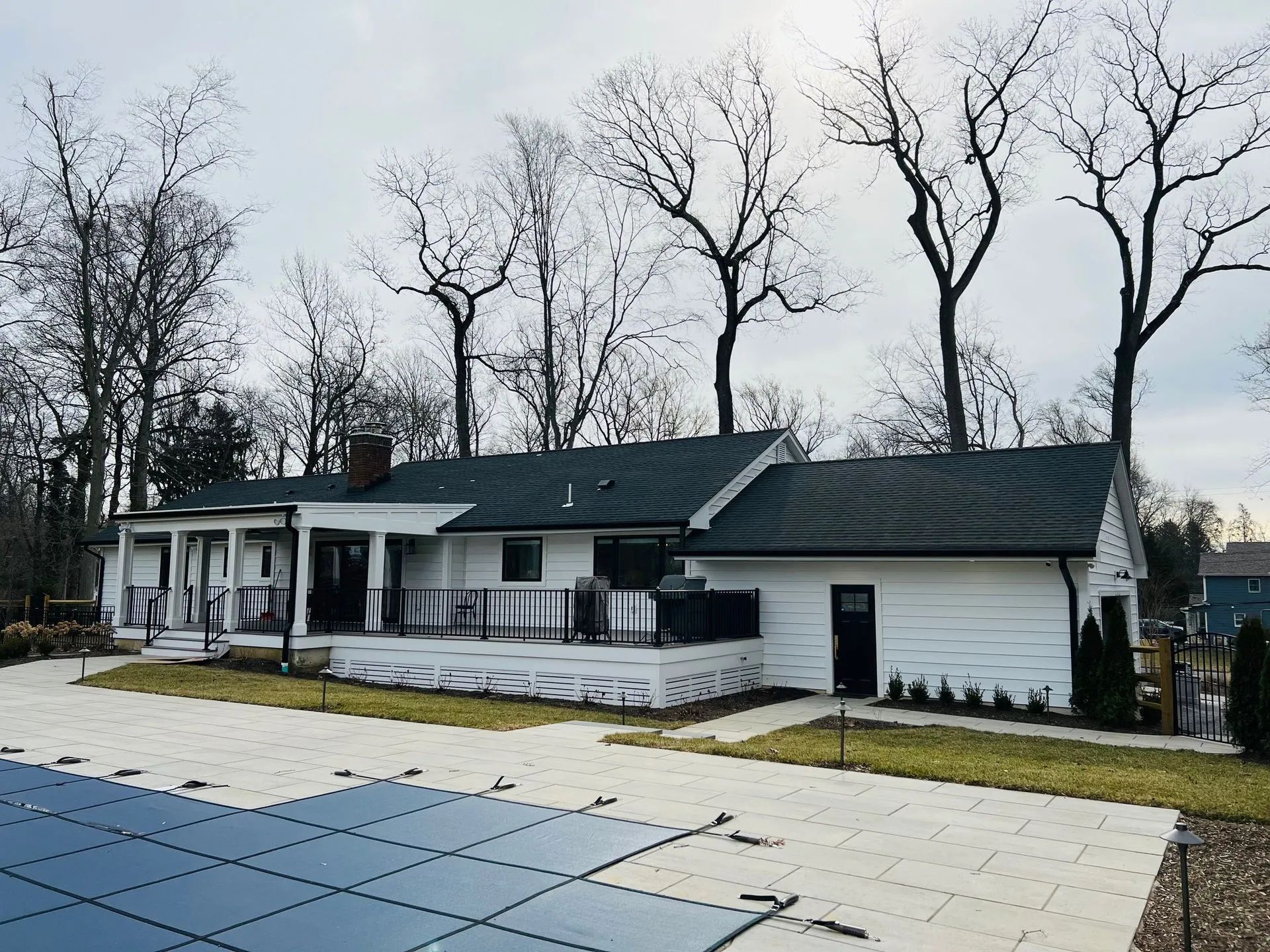 White single-story house with a porch and bare trees in a wintery yard