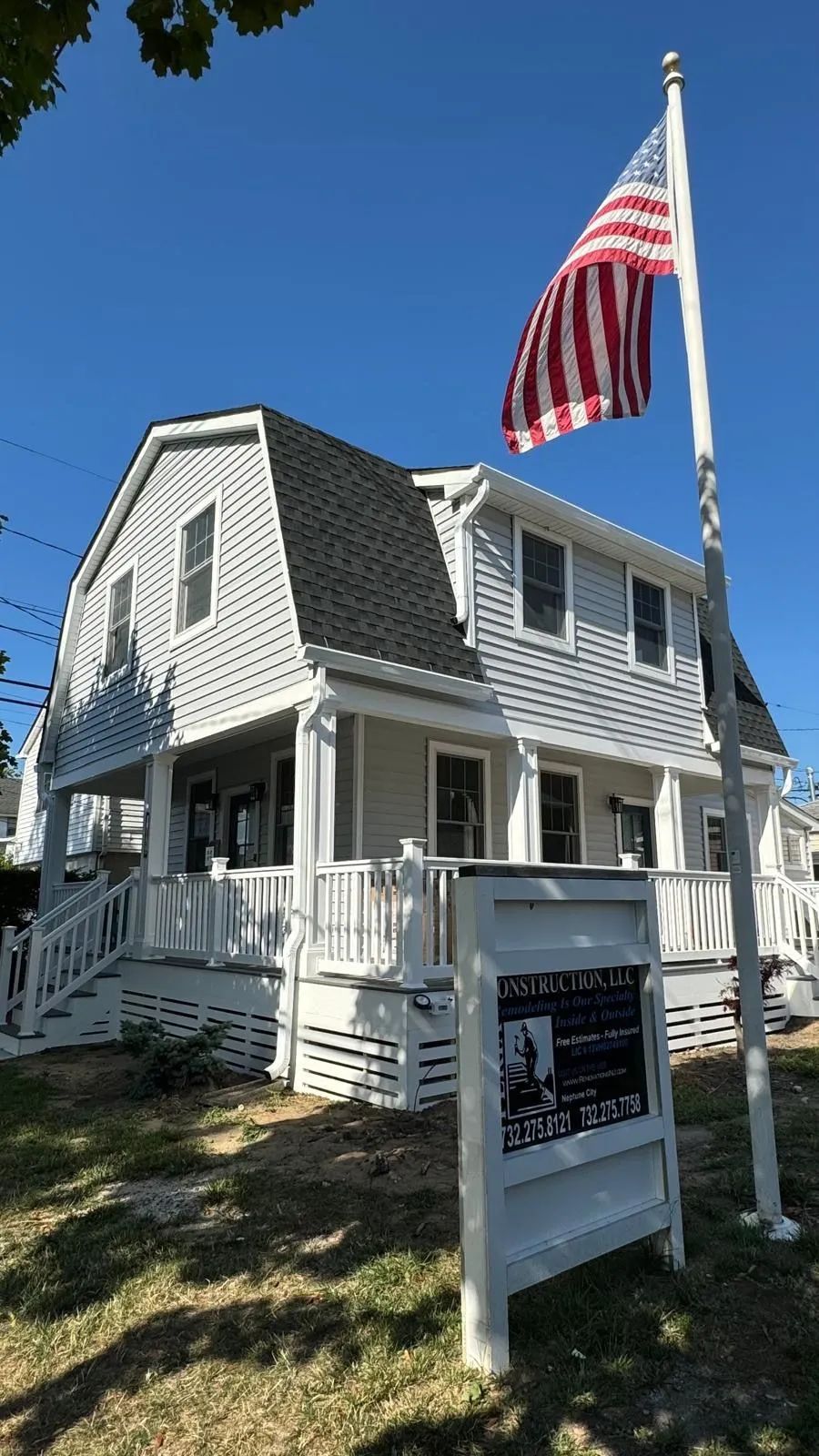 White house with porch and American flag on a sunny day