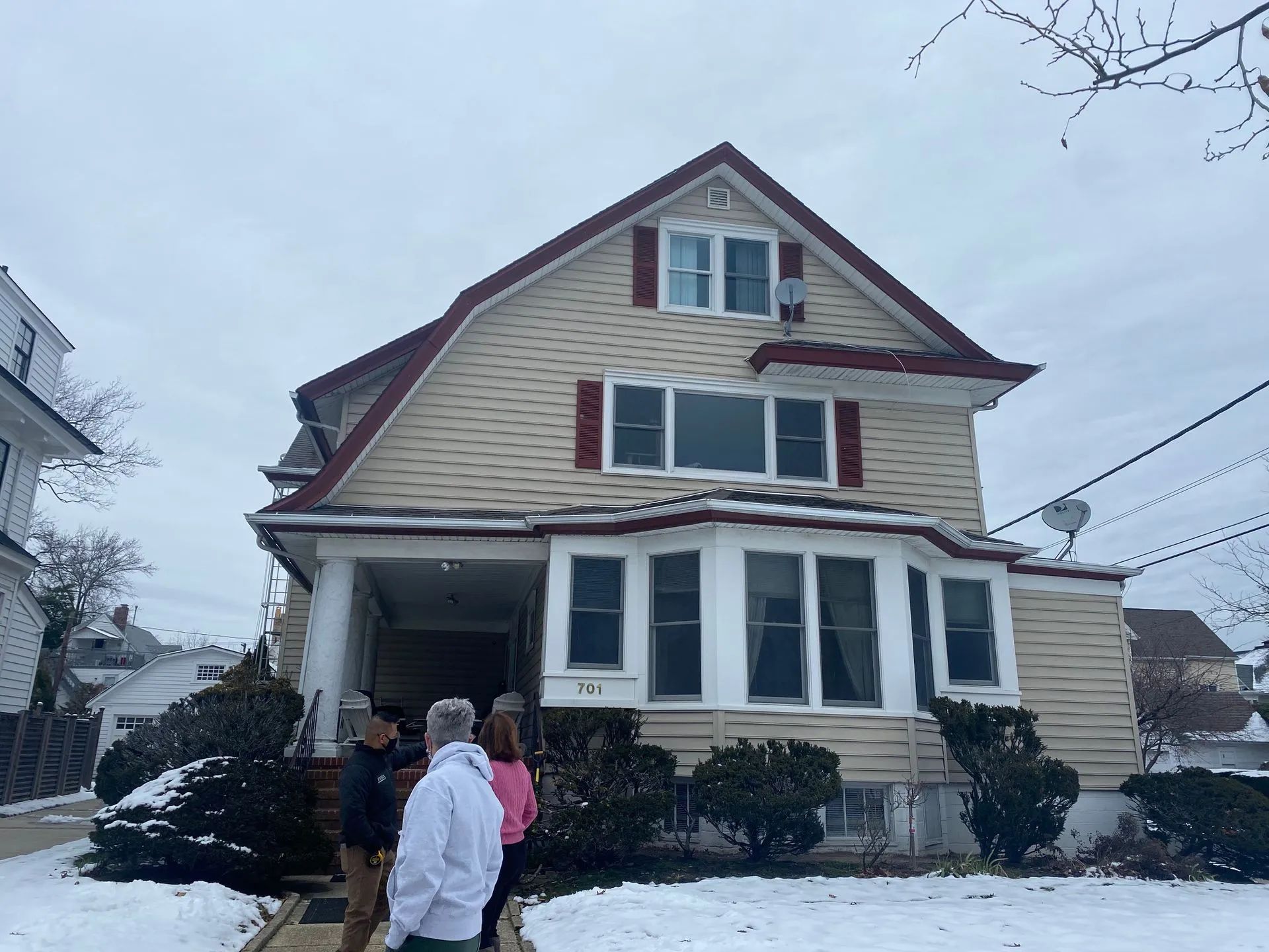 Snow-covered house with three people standing outside on a winter day