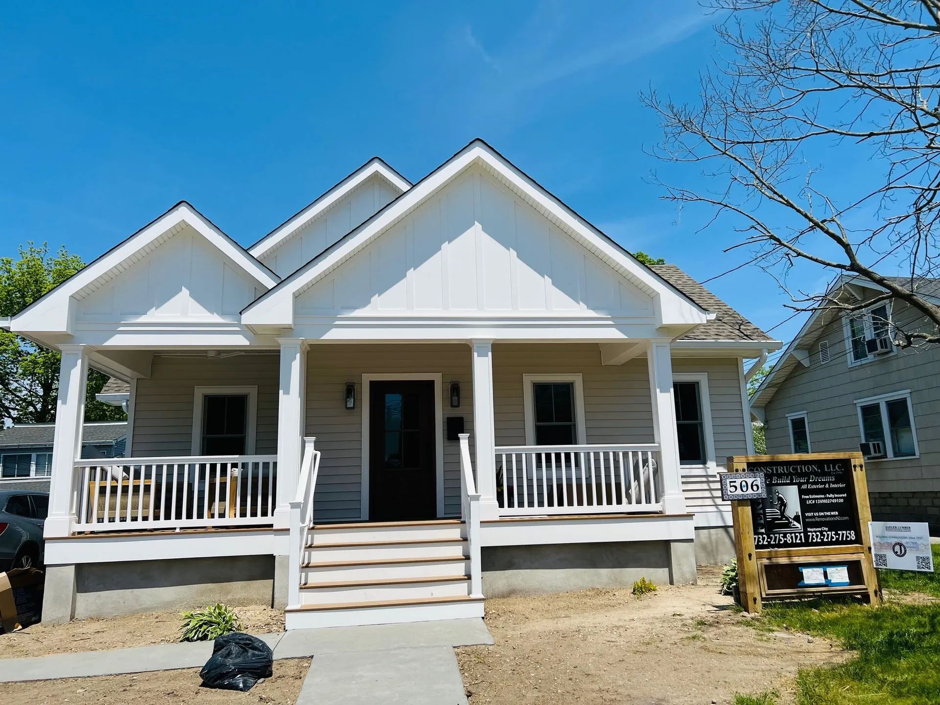 White house with front porch and steps under blue sky, with a small sign in the yard