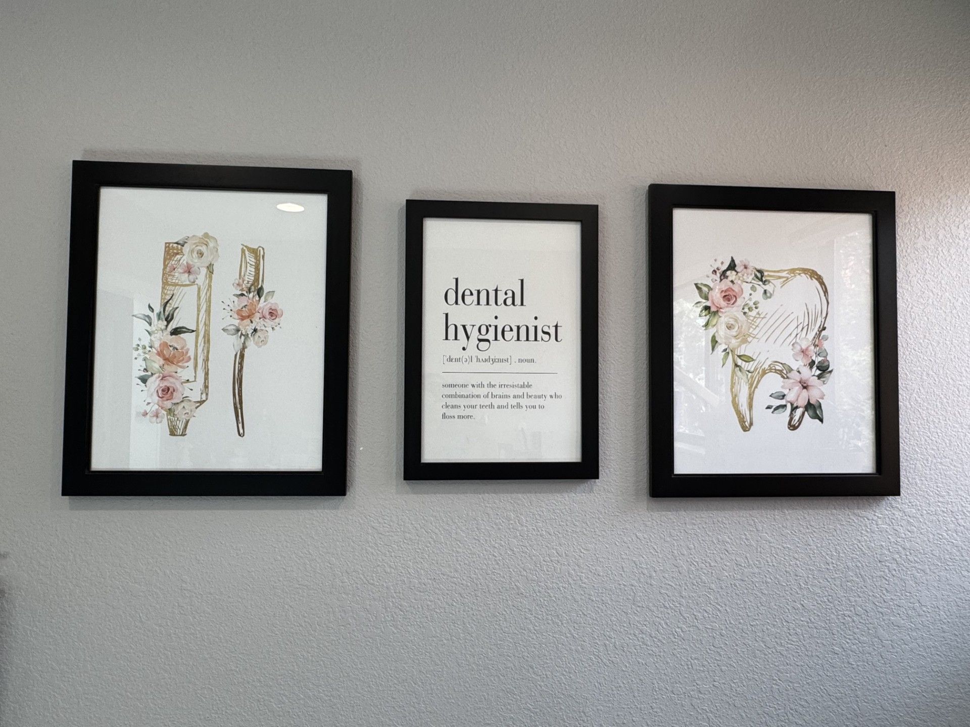 Three framed pictures are hanging on a wall in a dental office.