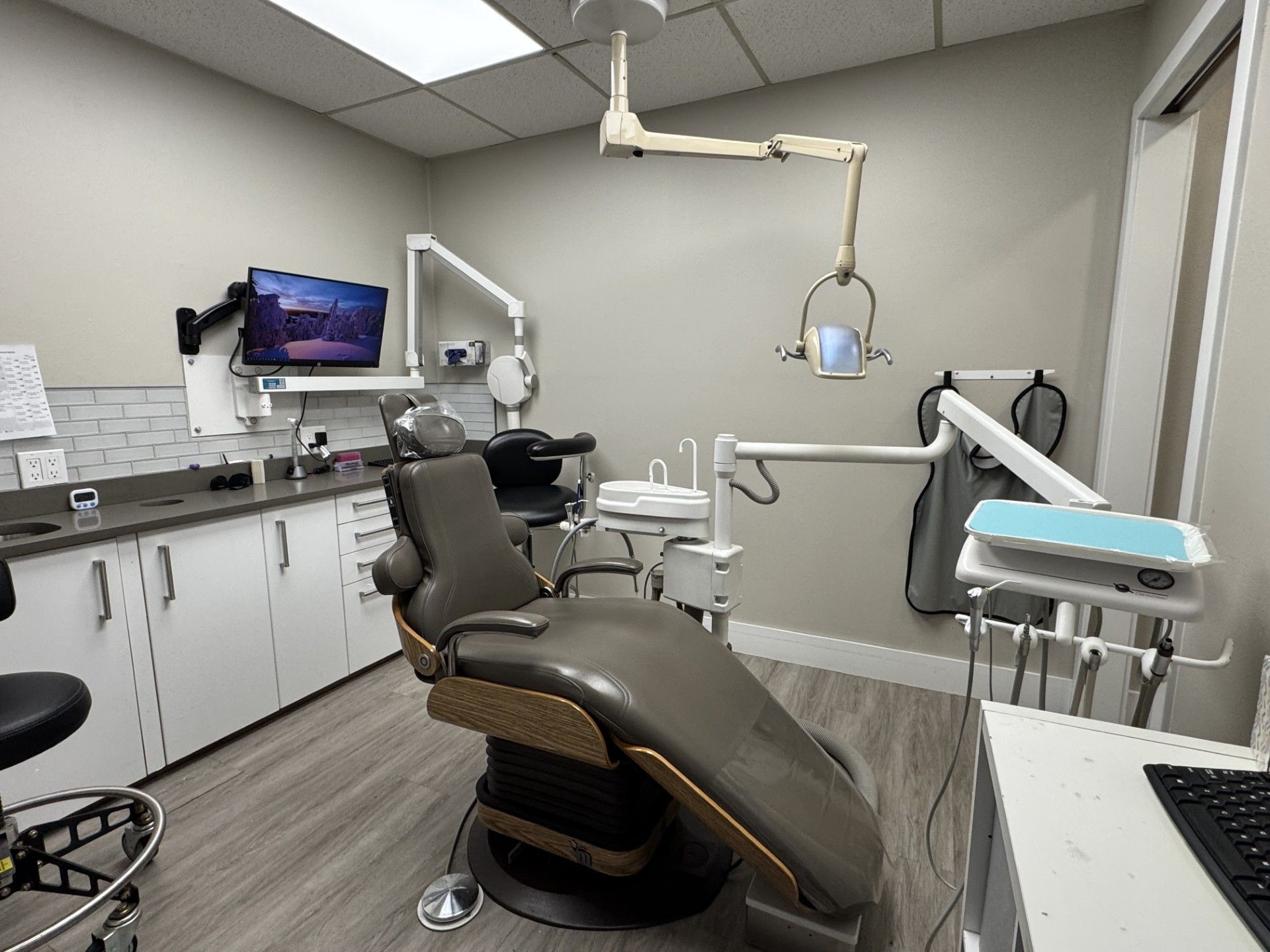 A dental office with a dental chair and a computer.