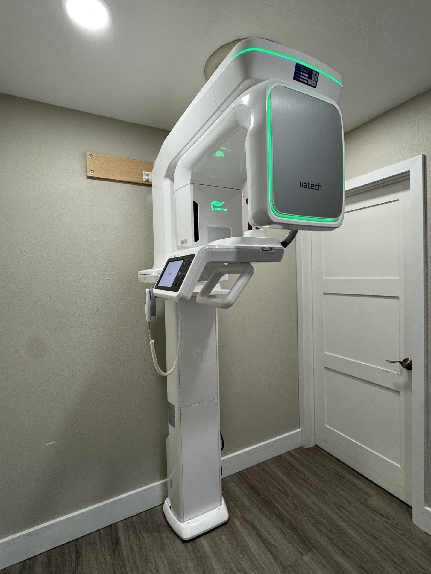 A large X-ray machine is sitting in a room next to a door.