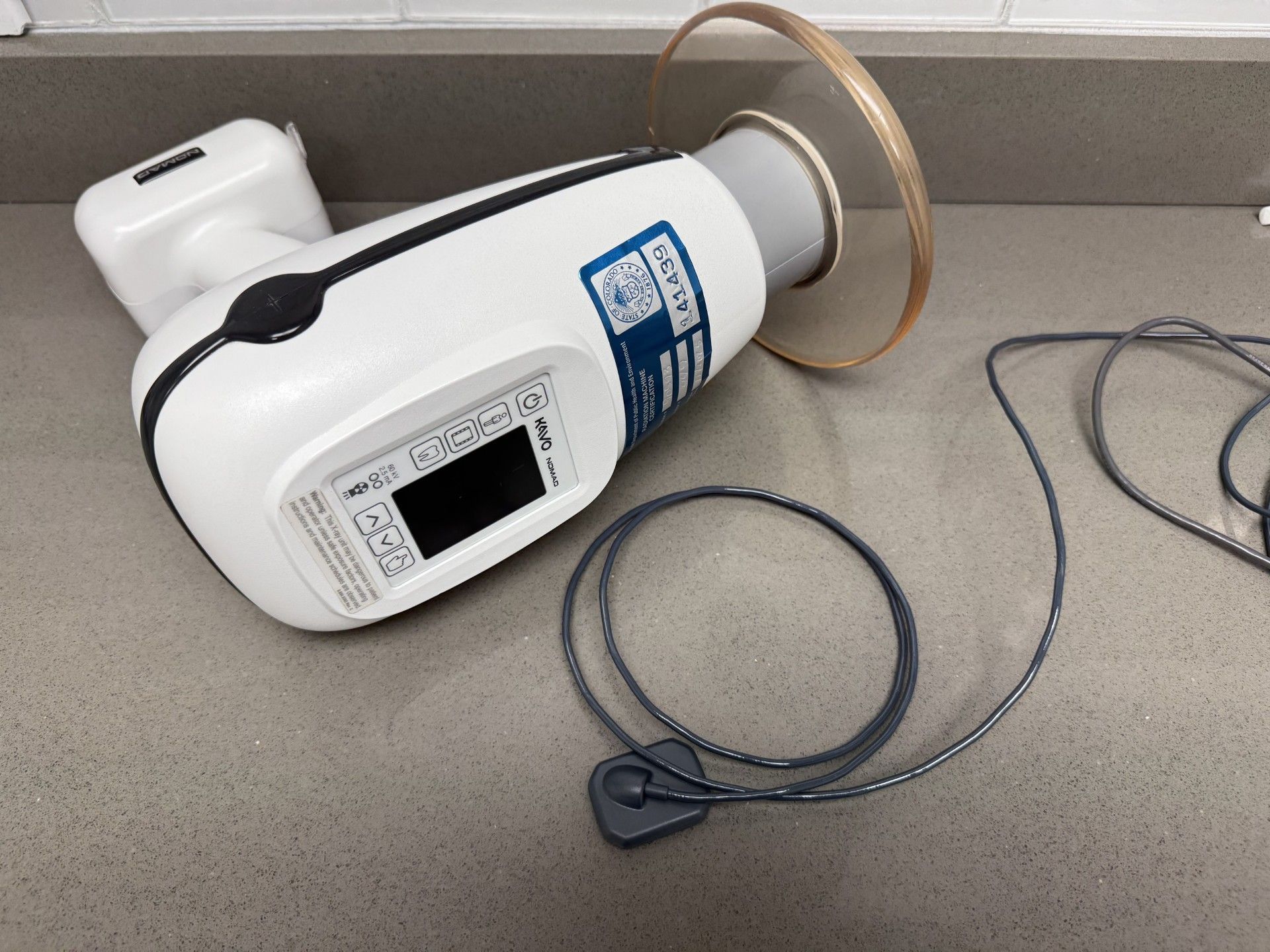 A dental X-ray machine is lying on a counter.