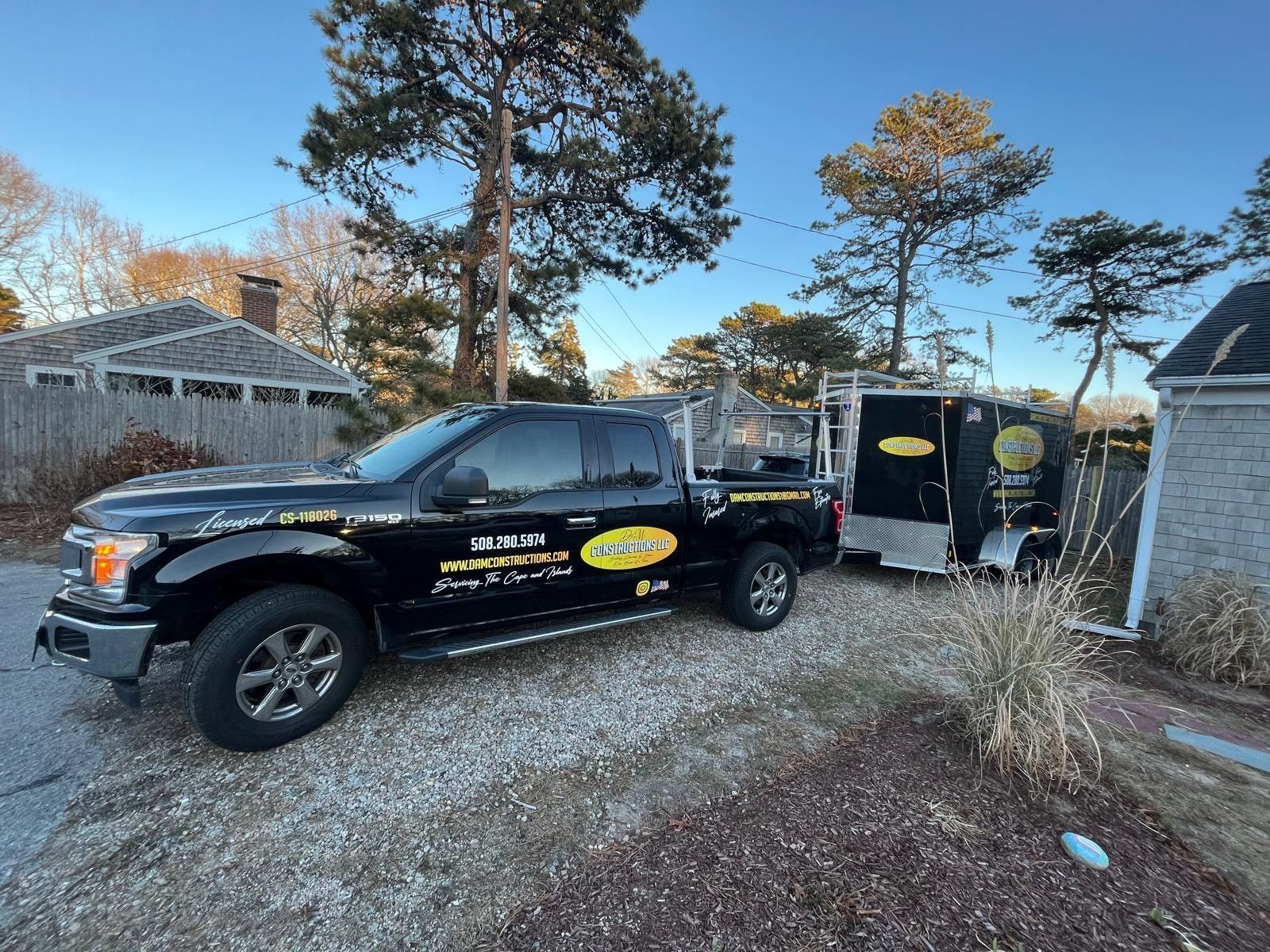 Black pickup truck with trailer parked on gravel driveway.