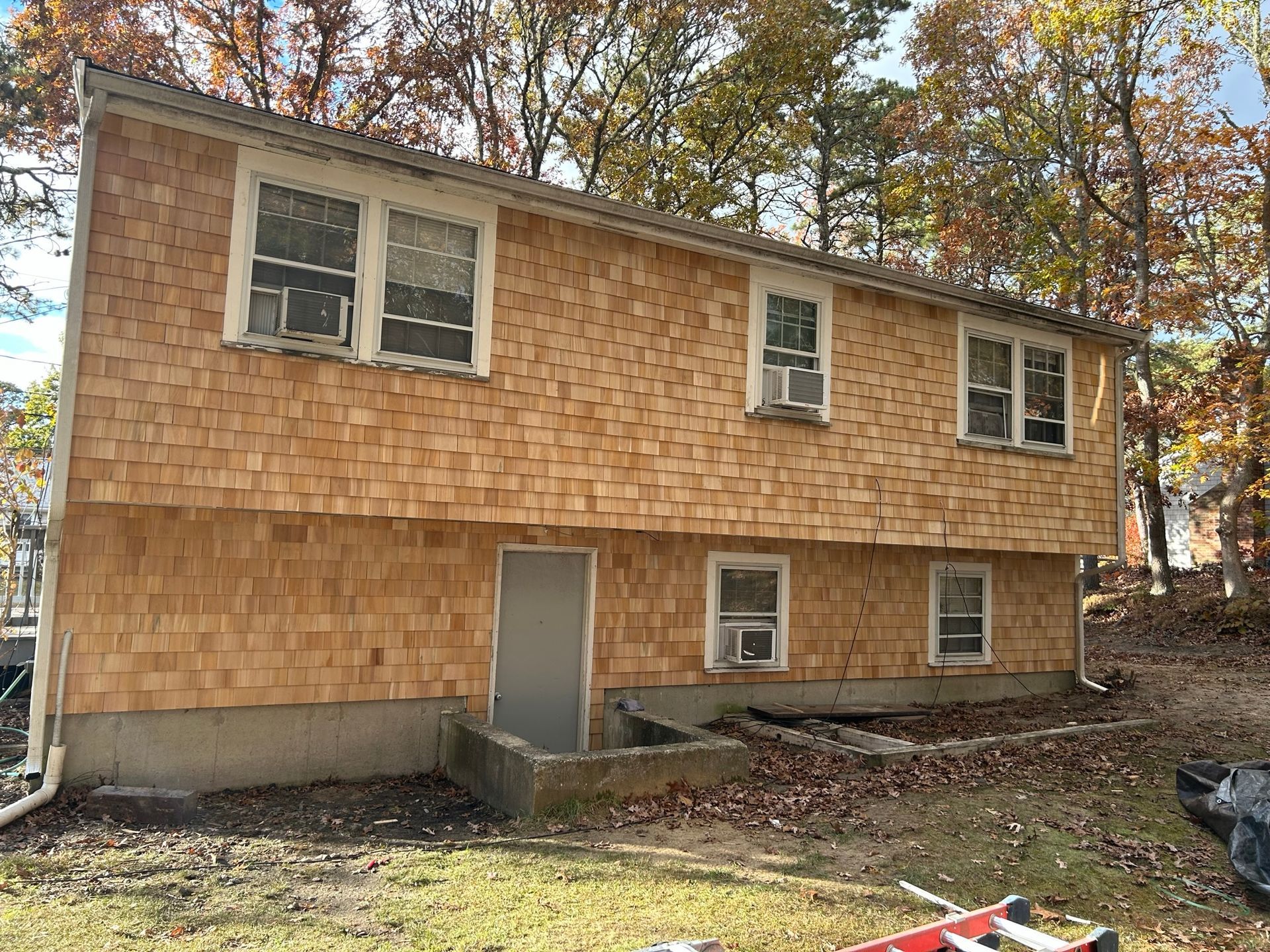 Two-story house with cedar shingle siding and several windows.