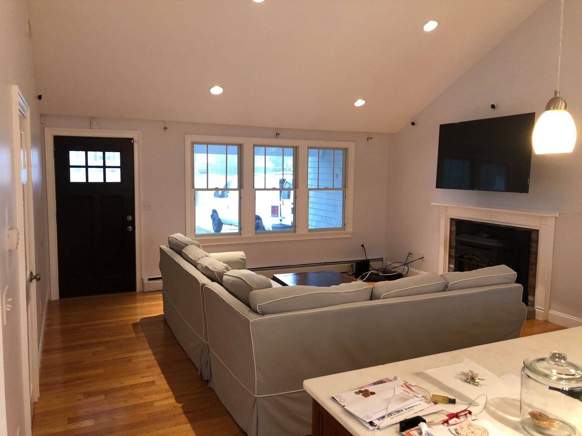 Living room with light gray sectional sofa, fireplace, and TV mounted on a wall.