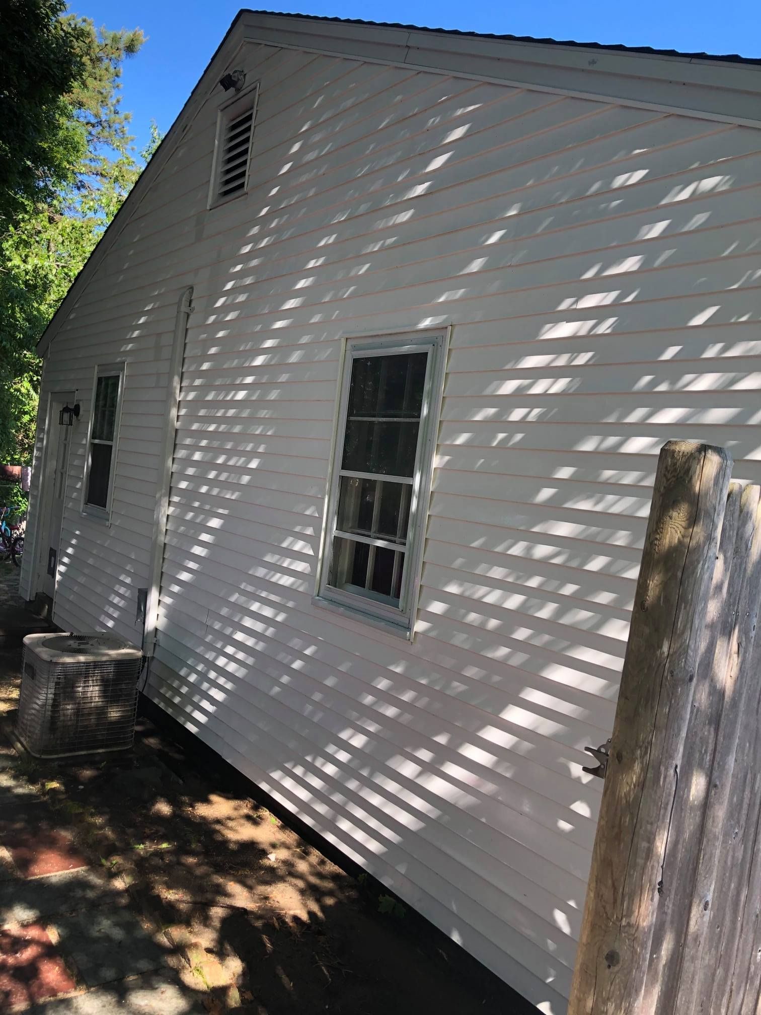 White house exterior with windows, siding, and roof on a sunny day.