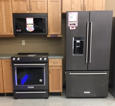 Kitchen appliances: oven, microwave, refrigerator, and cabinets, all in a showroom.
