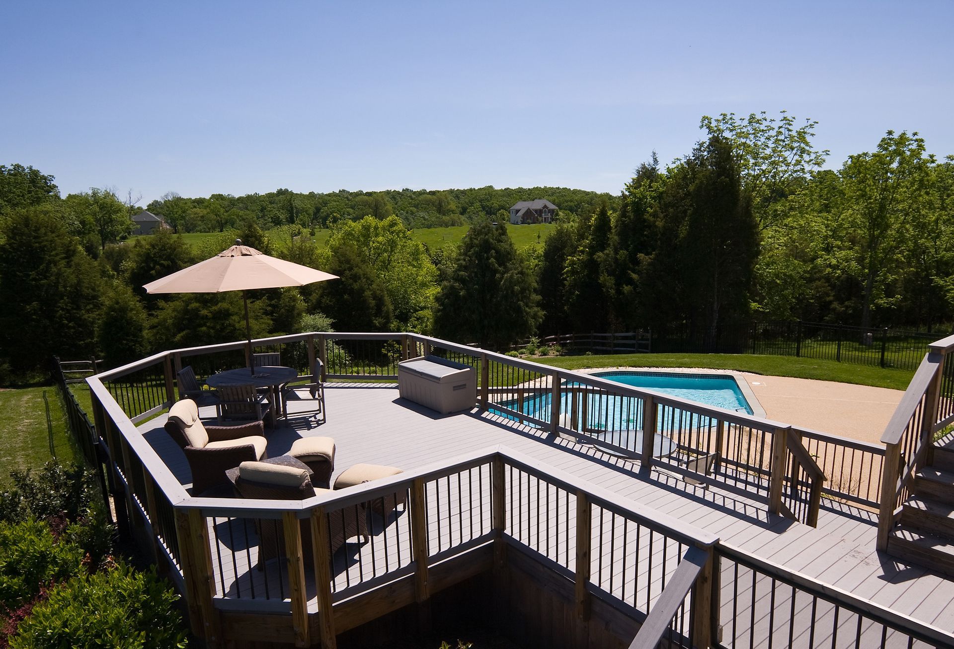 A large deck with a swimming pool in the background