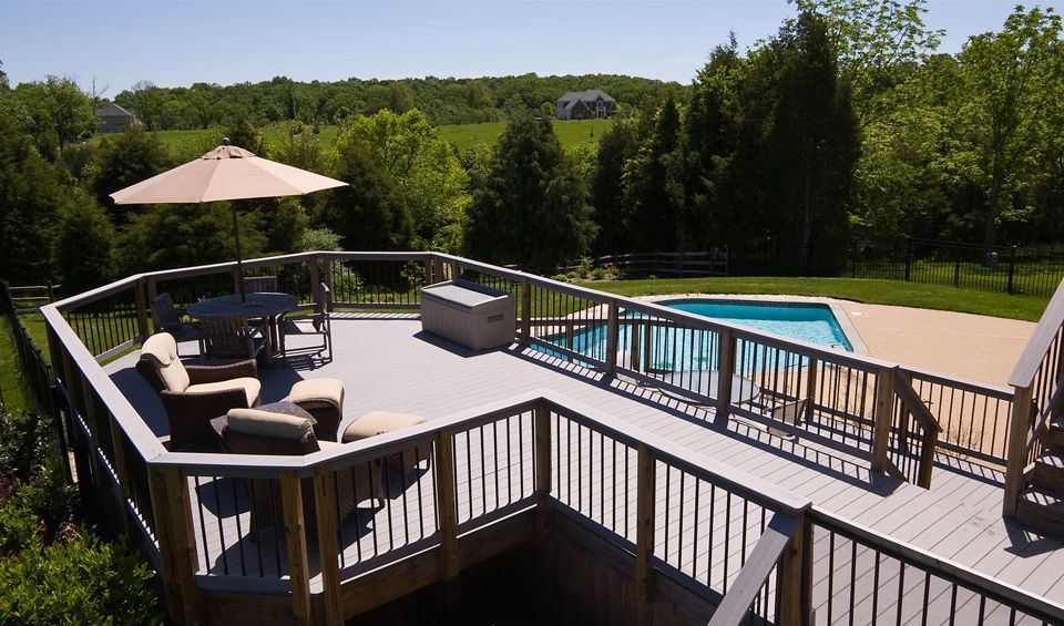 A large deck with a swimming pool in the background