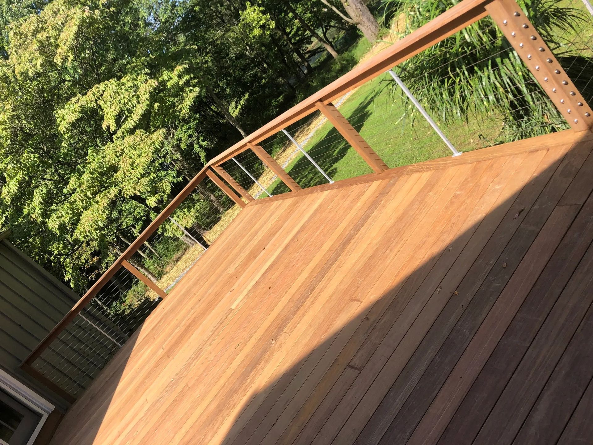 A wooden deck with a metal railing and trees in the background.
