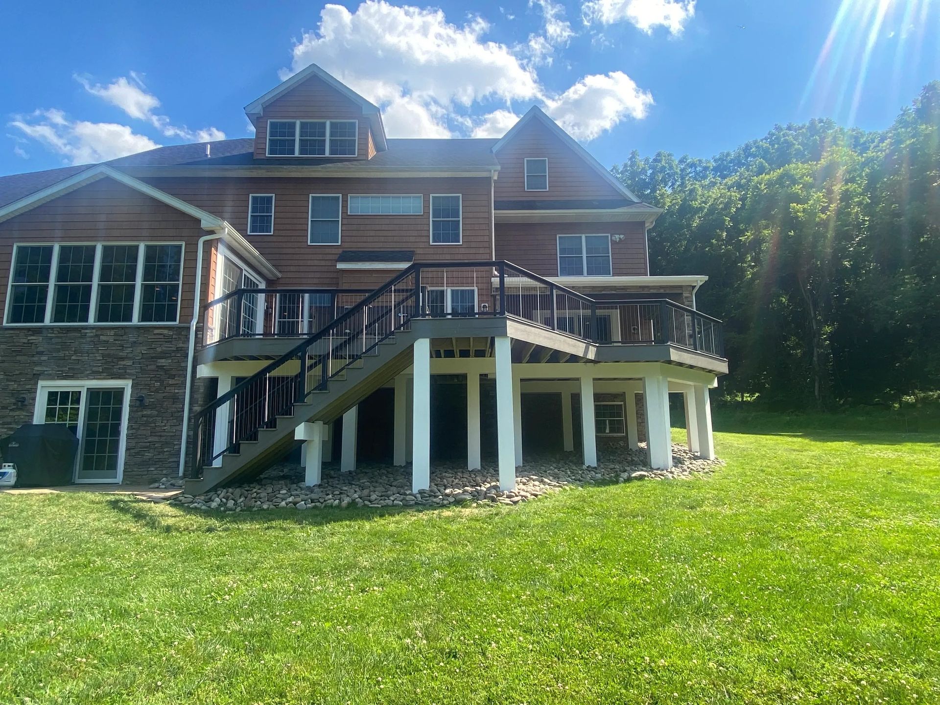 The back of a large house with a large deck and stairs.