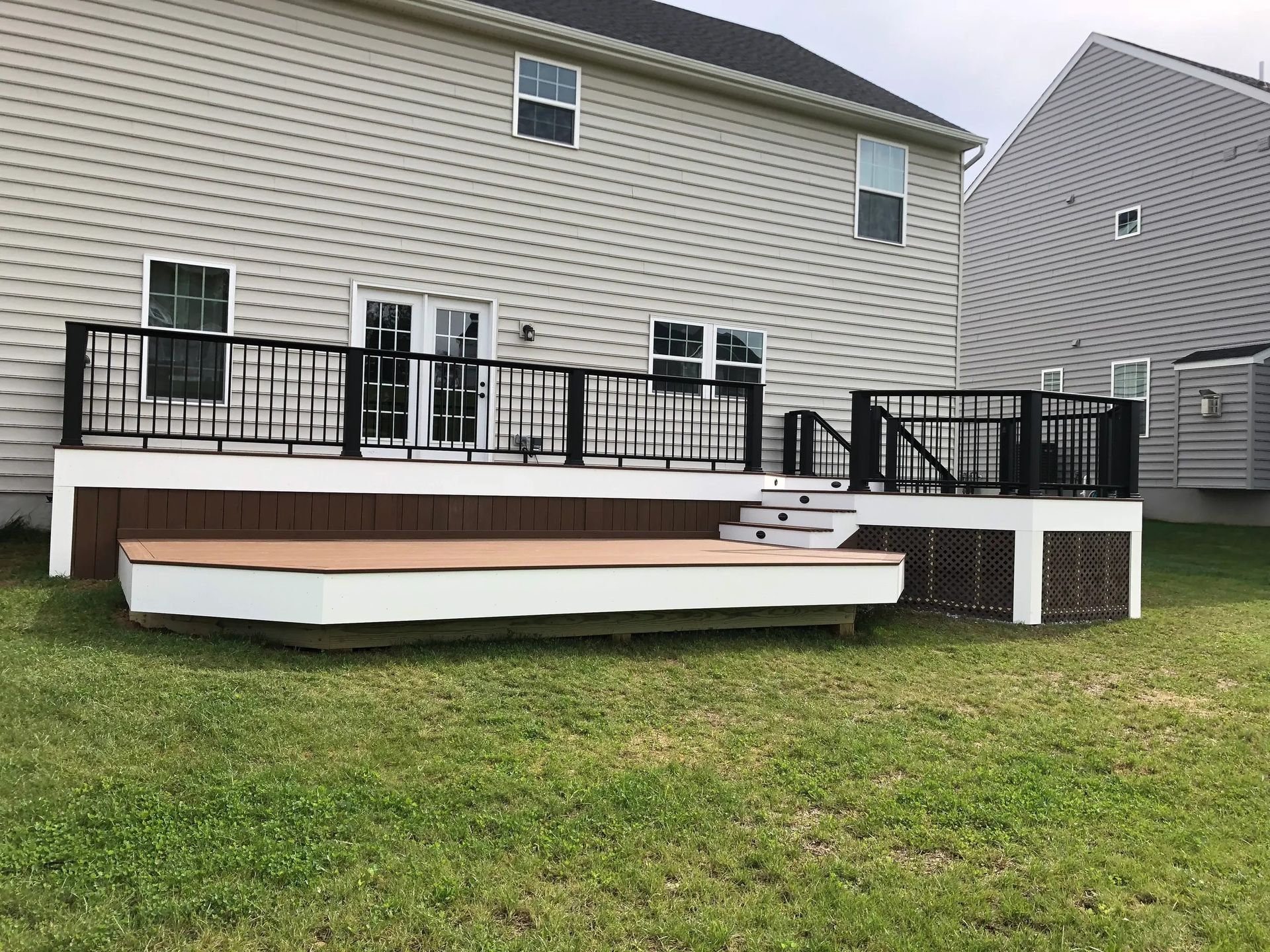 A large deck with stairs is in the backyard of a house.
