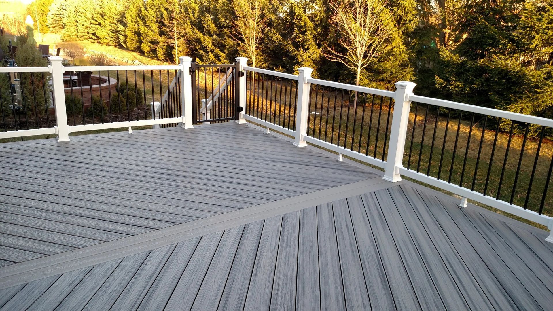 A large deck with a white railing and trees in the background