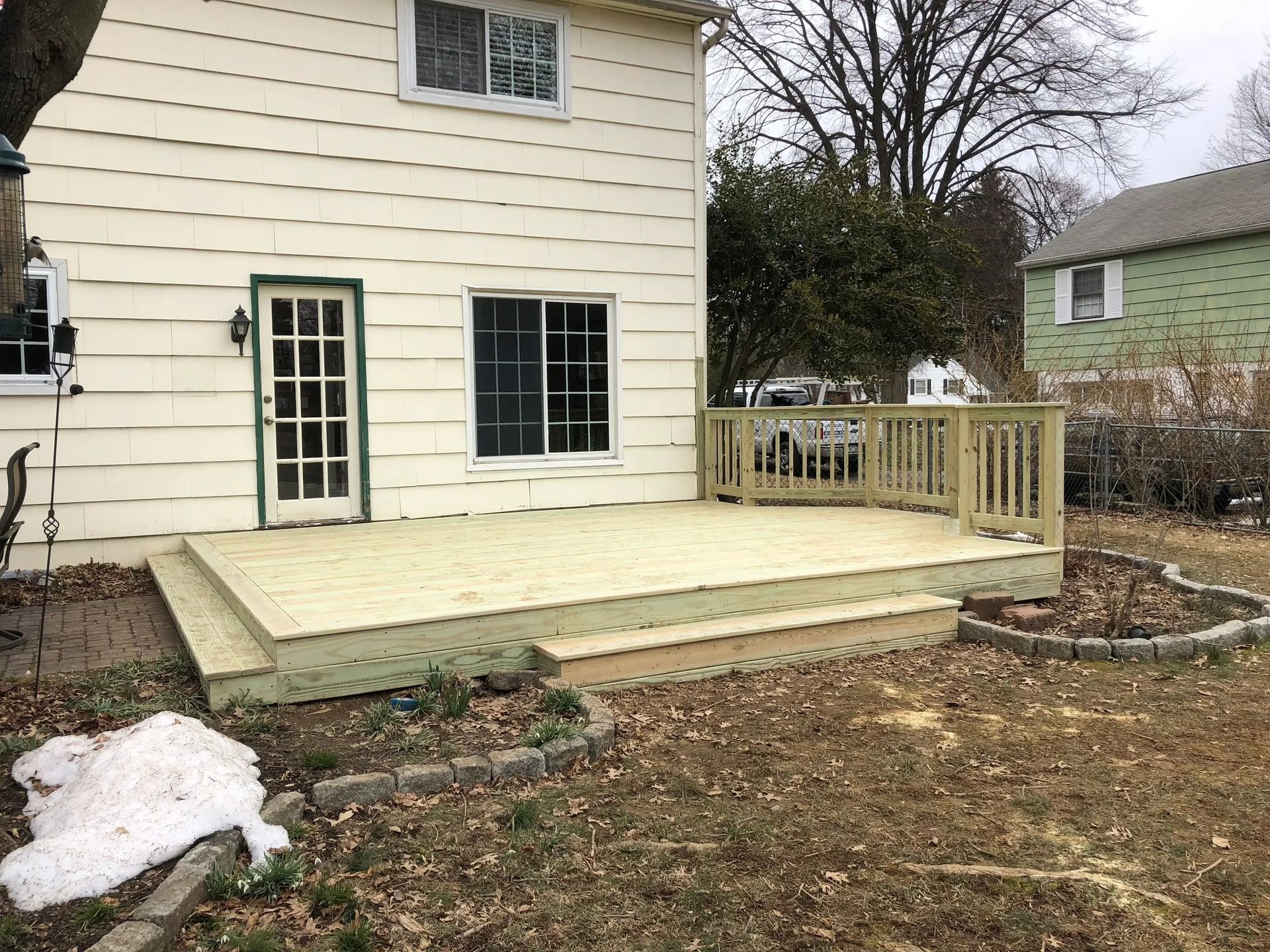 A white house with a wooden deck in front of it.