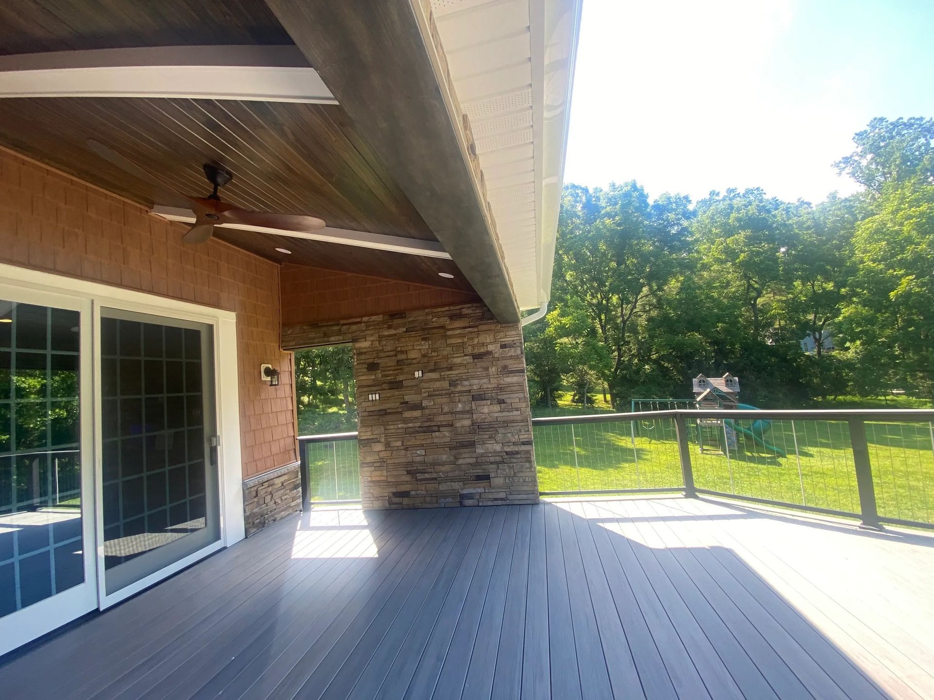 A large deck with a ceiling fan and sliding glass doors.