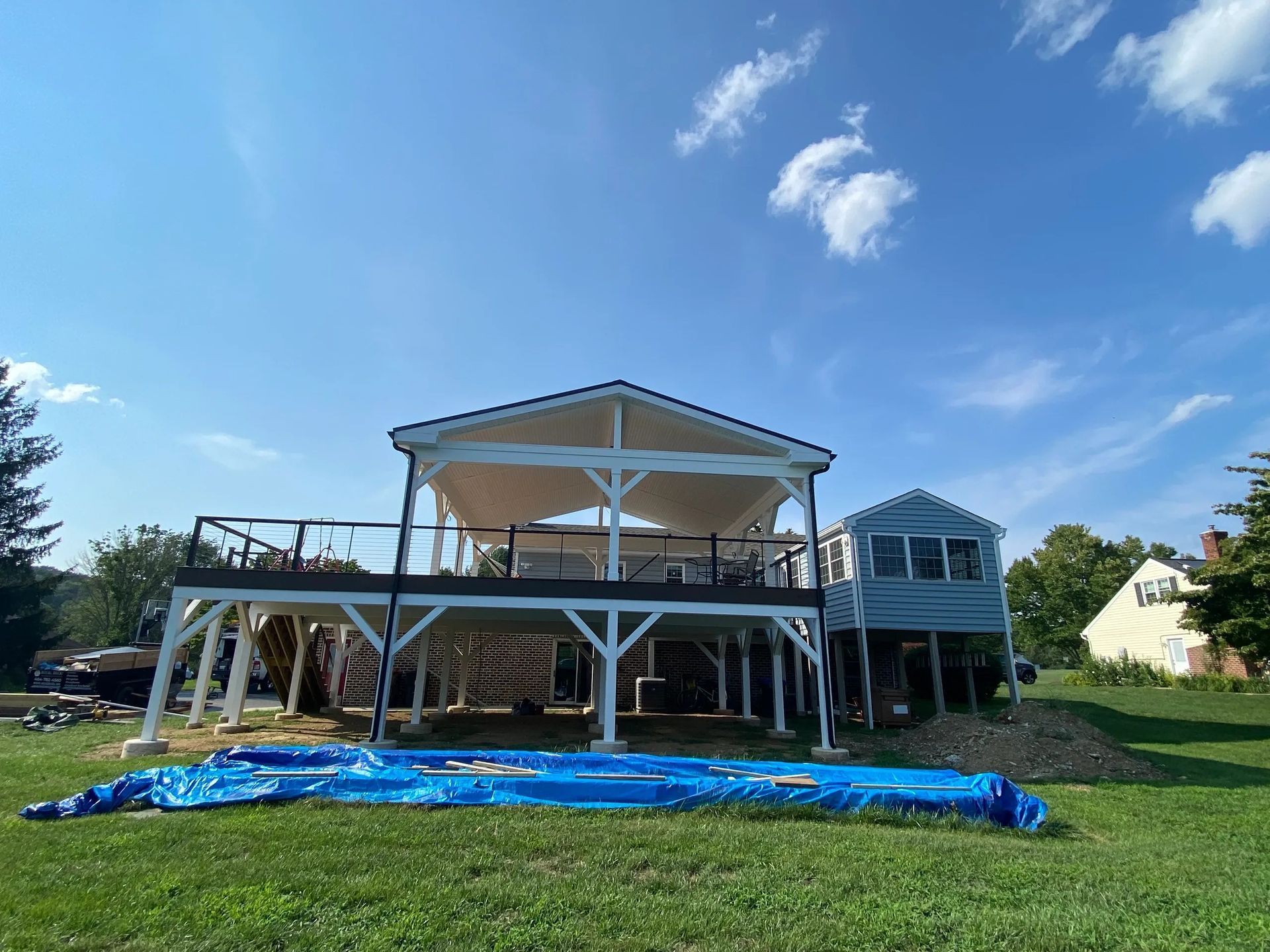 A large house with a large deck is sitting on top of a lush green field.