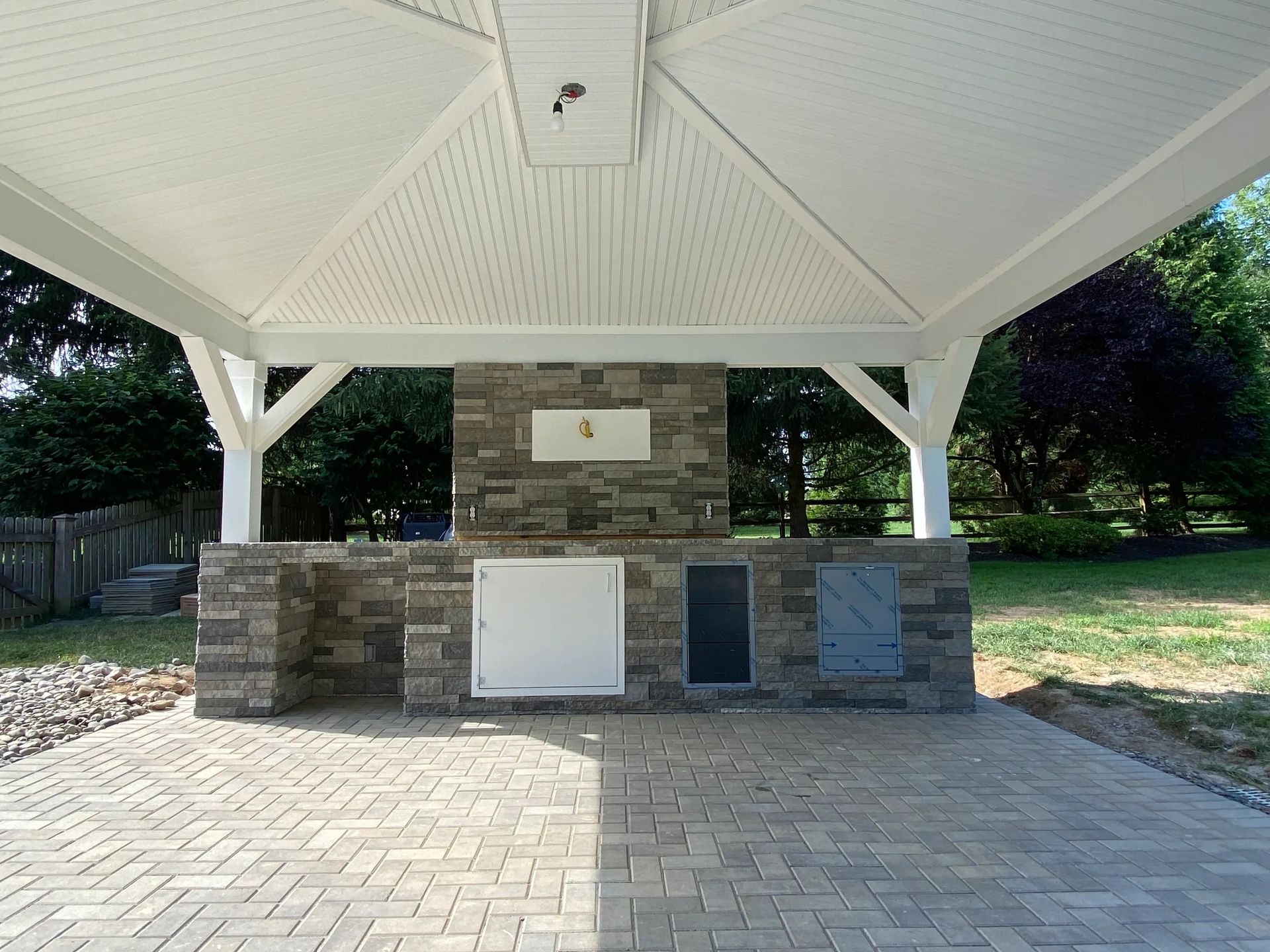 A gazebo with a stone wall and a white roof