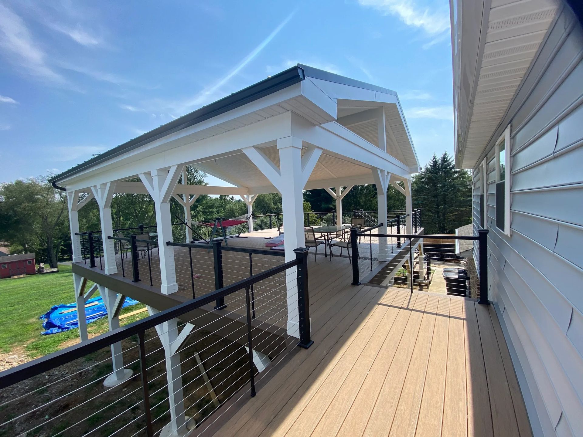 A large deck with a covered area and a swing on it.