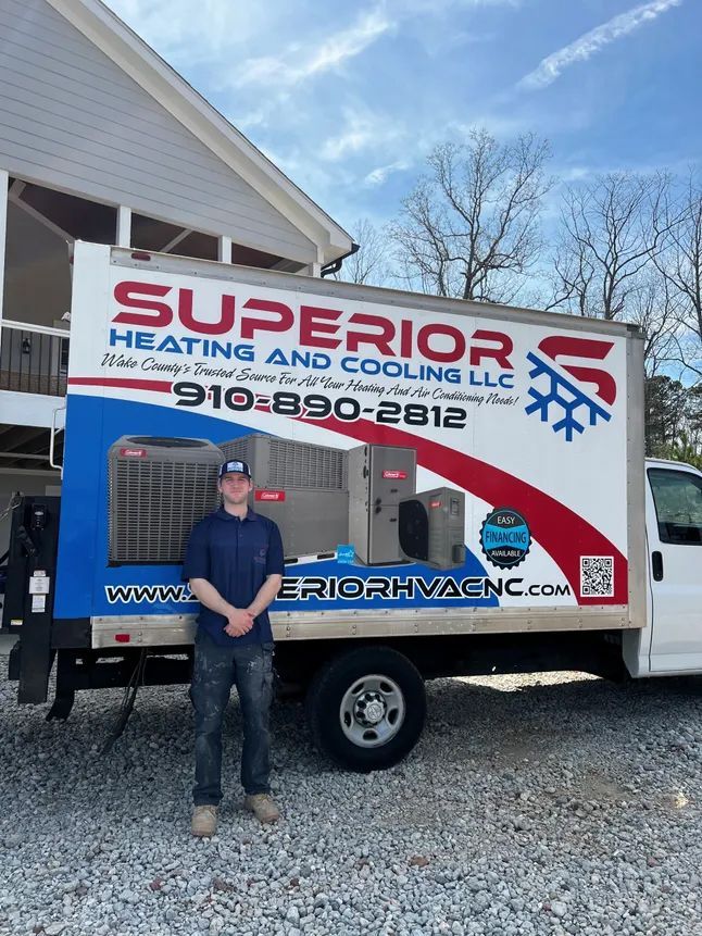 HVAC technician stands in front of a Superior Heating & Cooling truck. The truck has logos and equipment.