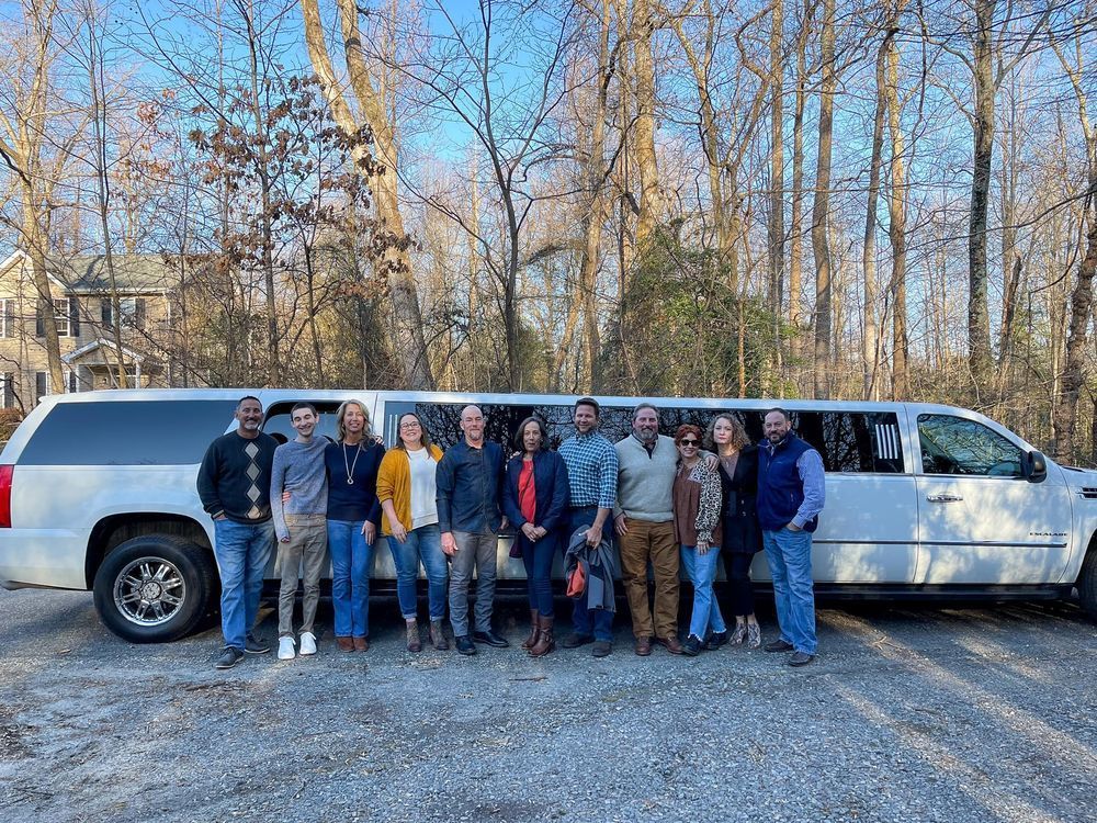 A group of people are posing for a picture in front of a limousine.