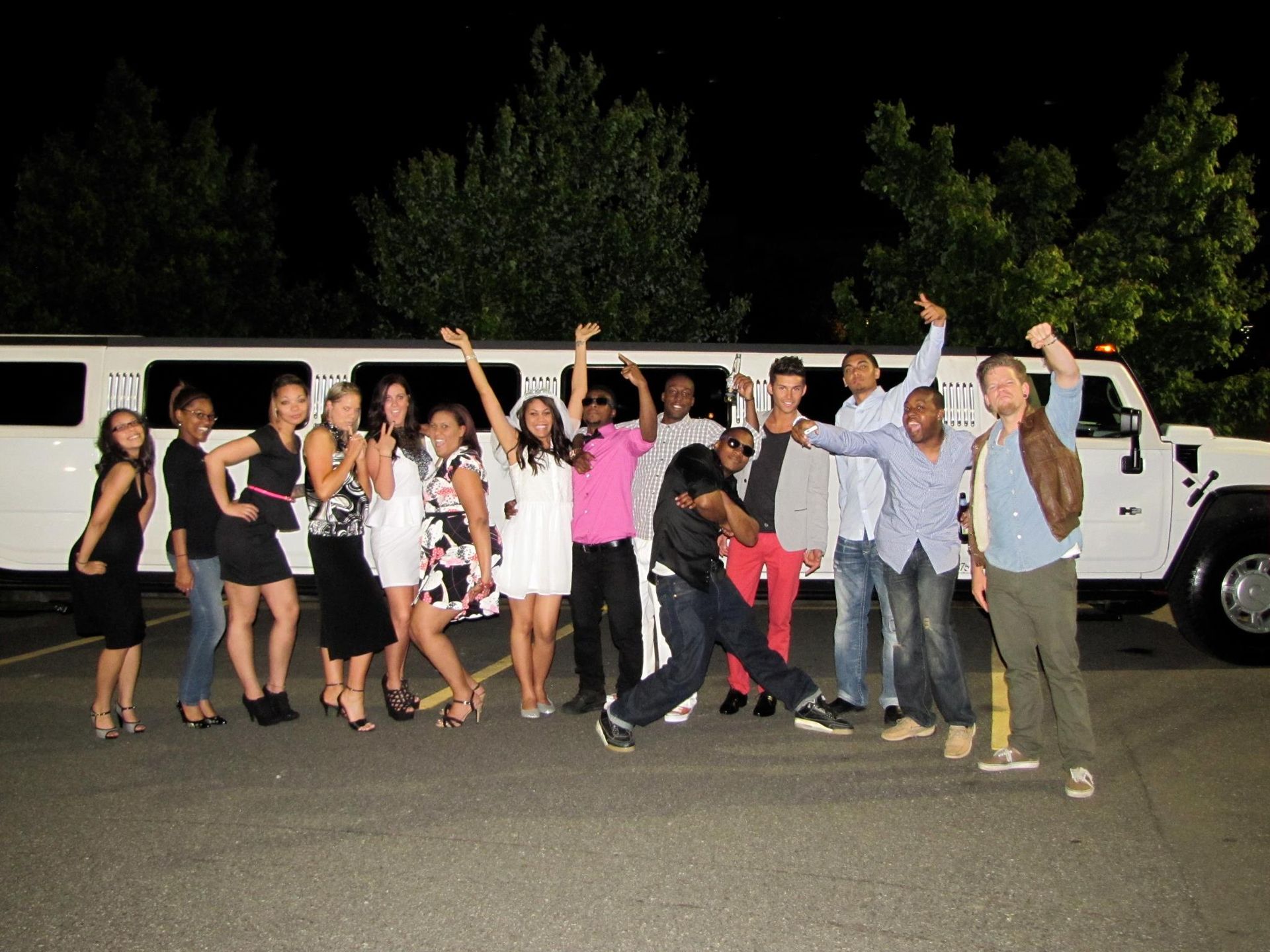 A group of people posing in front of a white limousine.