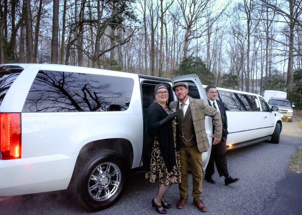 A man and woman are standing in front of a white limousine.