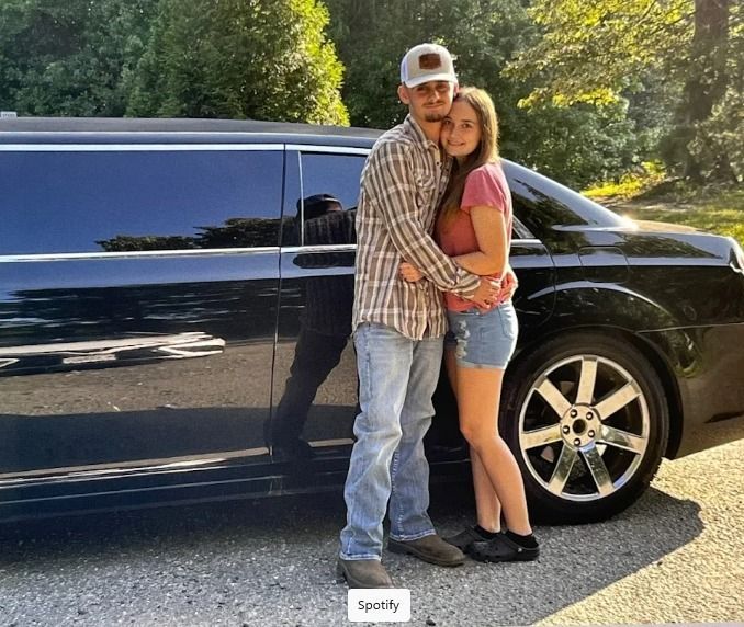 A man and a woman hugging in front of a black van.
