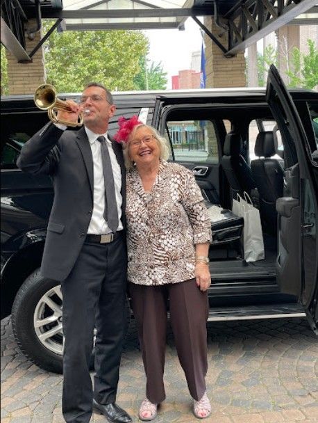 A man in a suit and tie is playing a trumpet next to a woman.