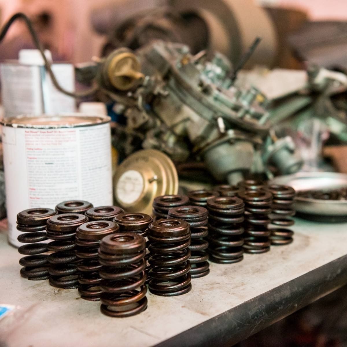 Stacks of dark metal springs and engine parts on a workbench in a workshop