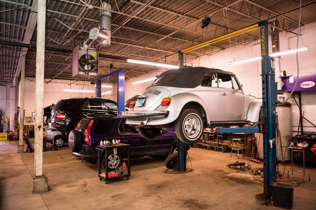 Auto repair shop with a silver car lifted on a hoist and another black car in the background