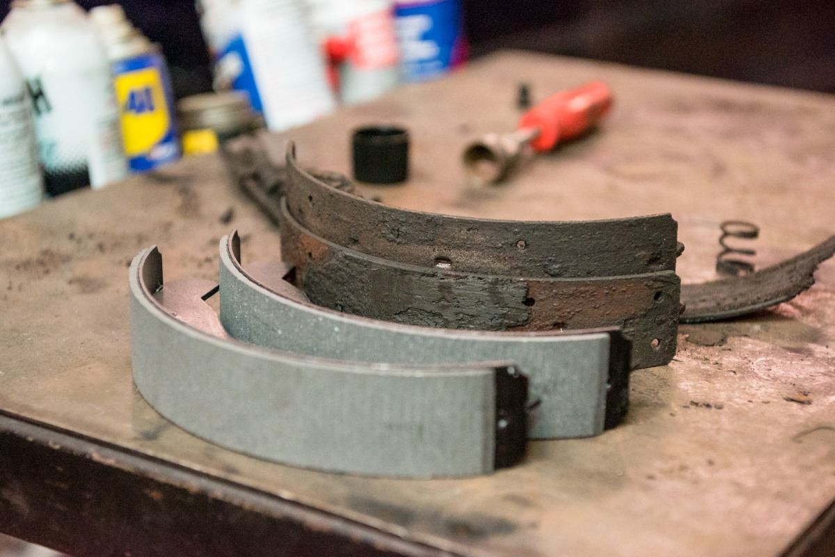 Stacked car brake shoes on a workbench with tools in the background
