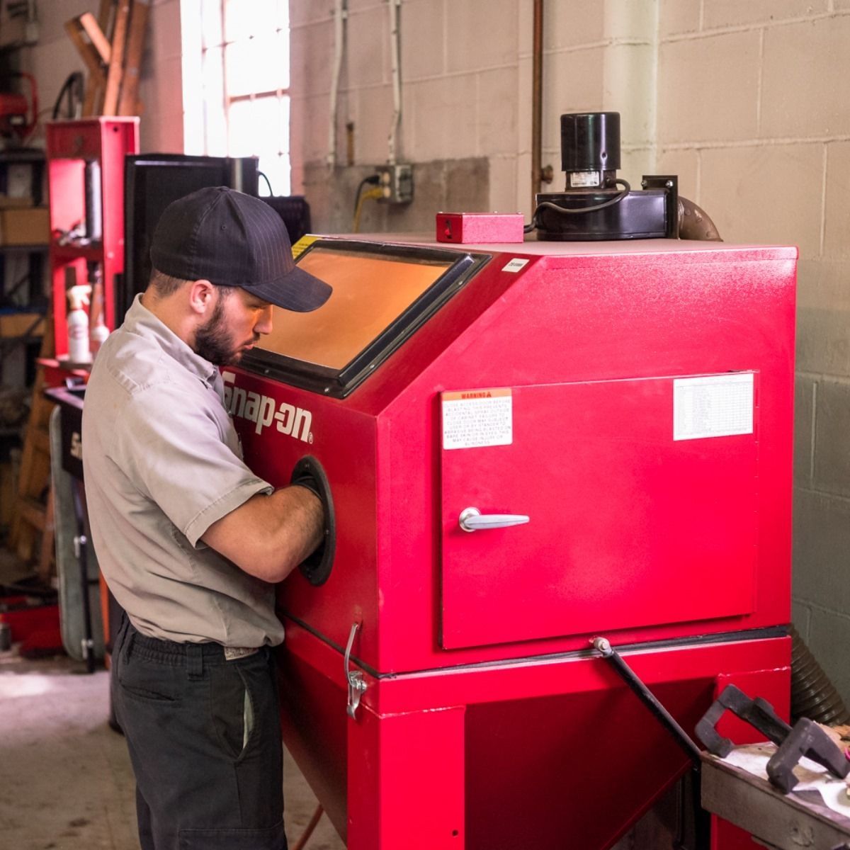 Worker operating a red industrial machine in a workshop