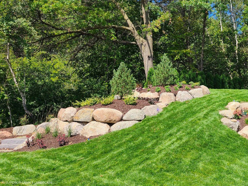 A lush green lawn with rocks and trees in the background.