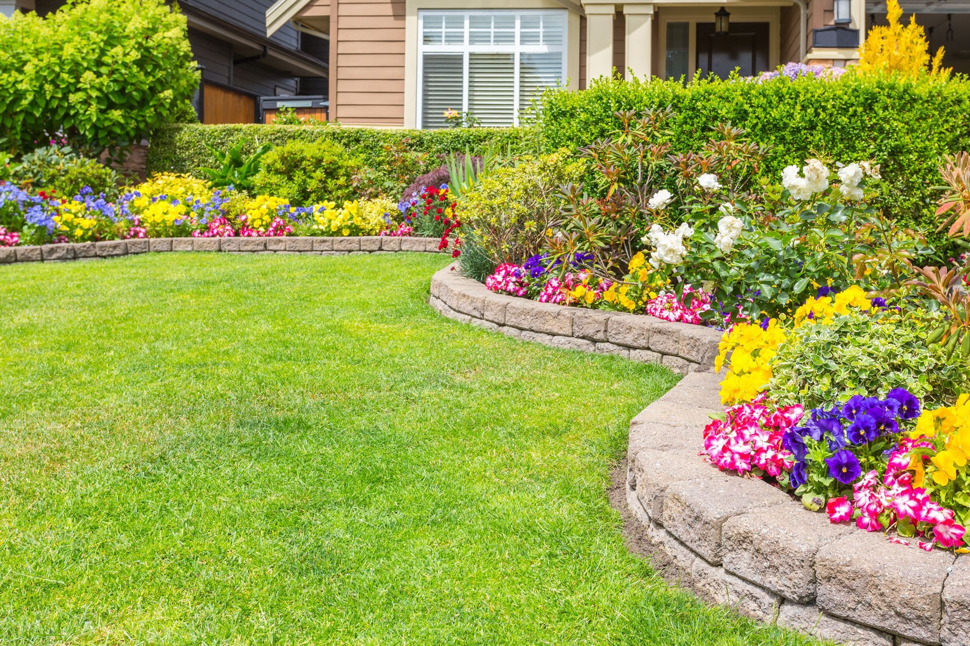 A lush green lawn with flowers in front of a house.
