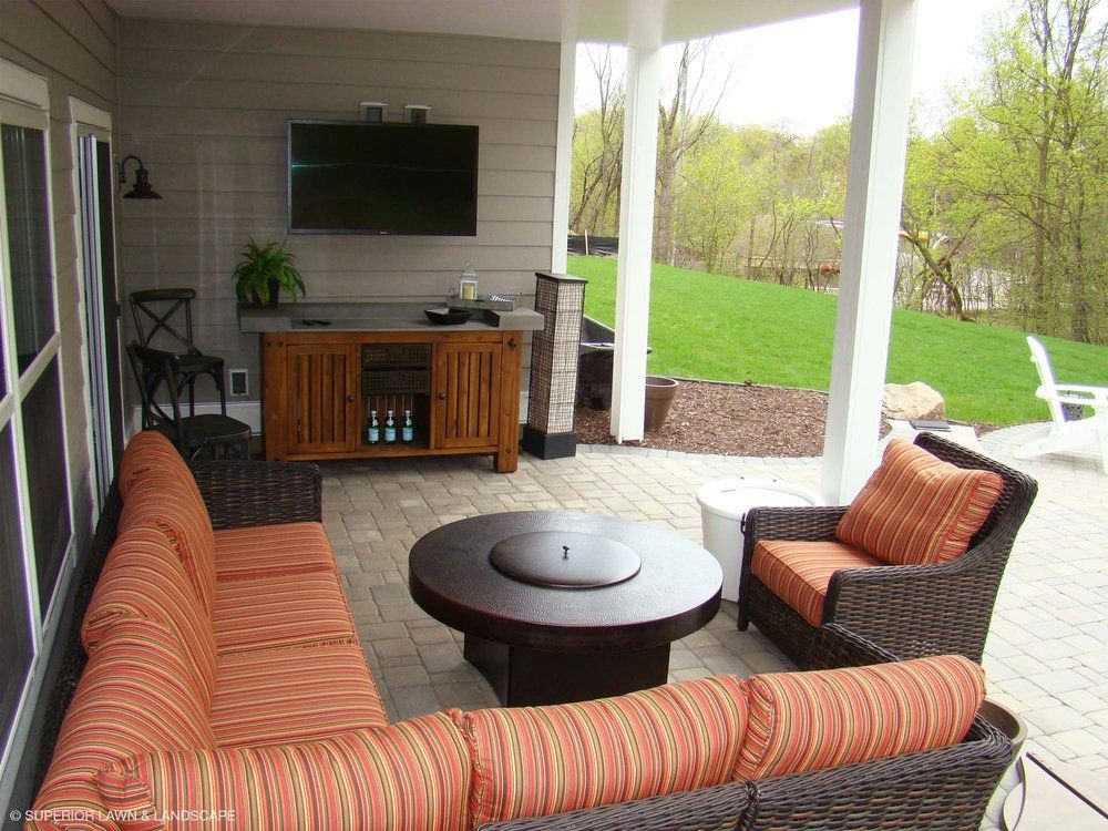 A patio with a couch and chairs and a flat screen tv