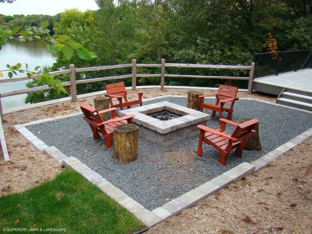A fire pit with chairs around it and a fence around it