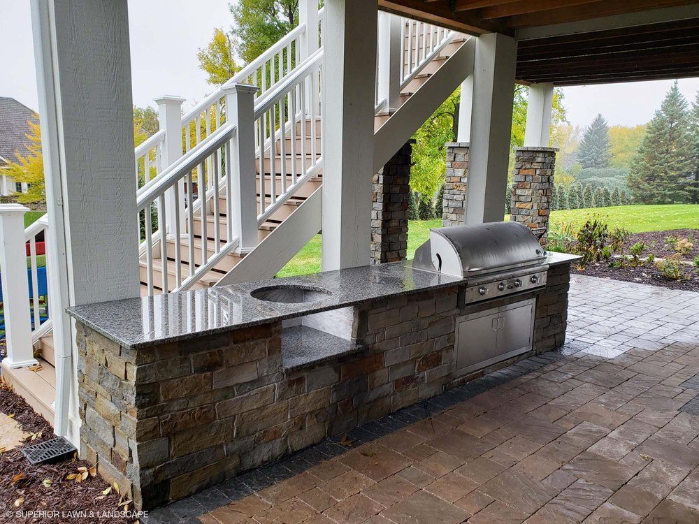 An outdoor kitchen with a grill and stairs in the background.