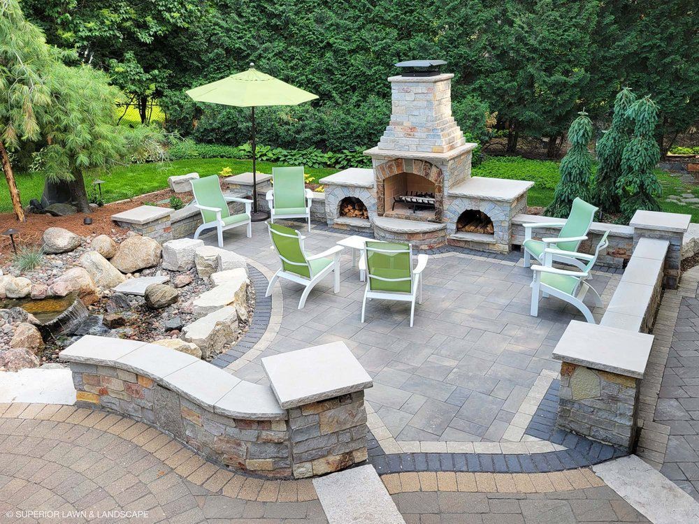 A patio with a fireplace and chairs and umbrellas