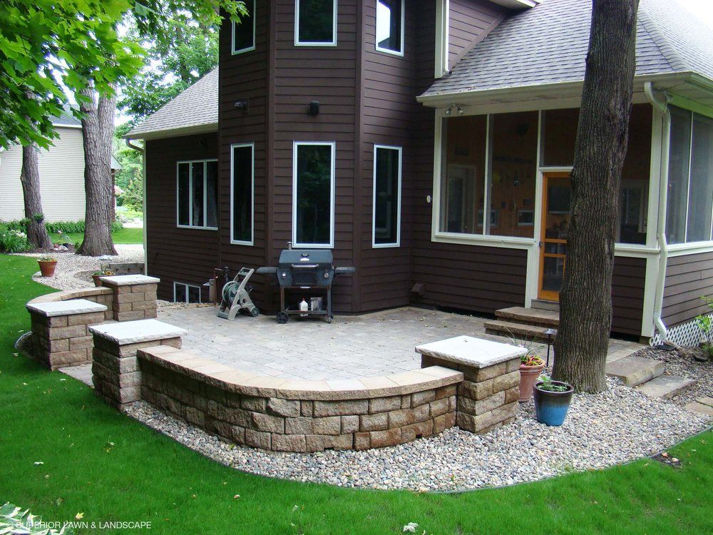 A brown house with a screened in porch and a grill
