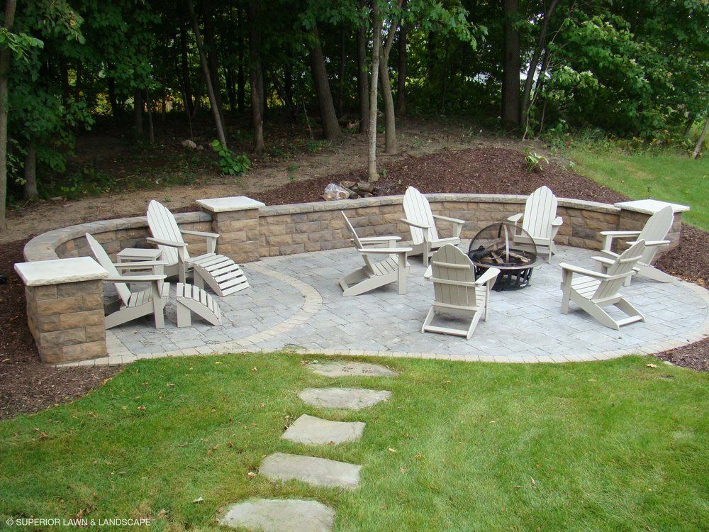 A group of chairs are sitting around a fire pit in a backyard.