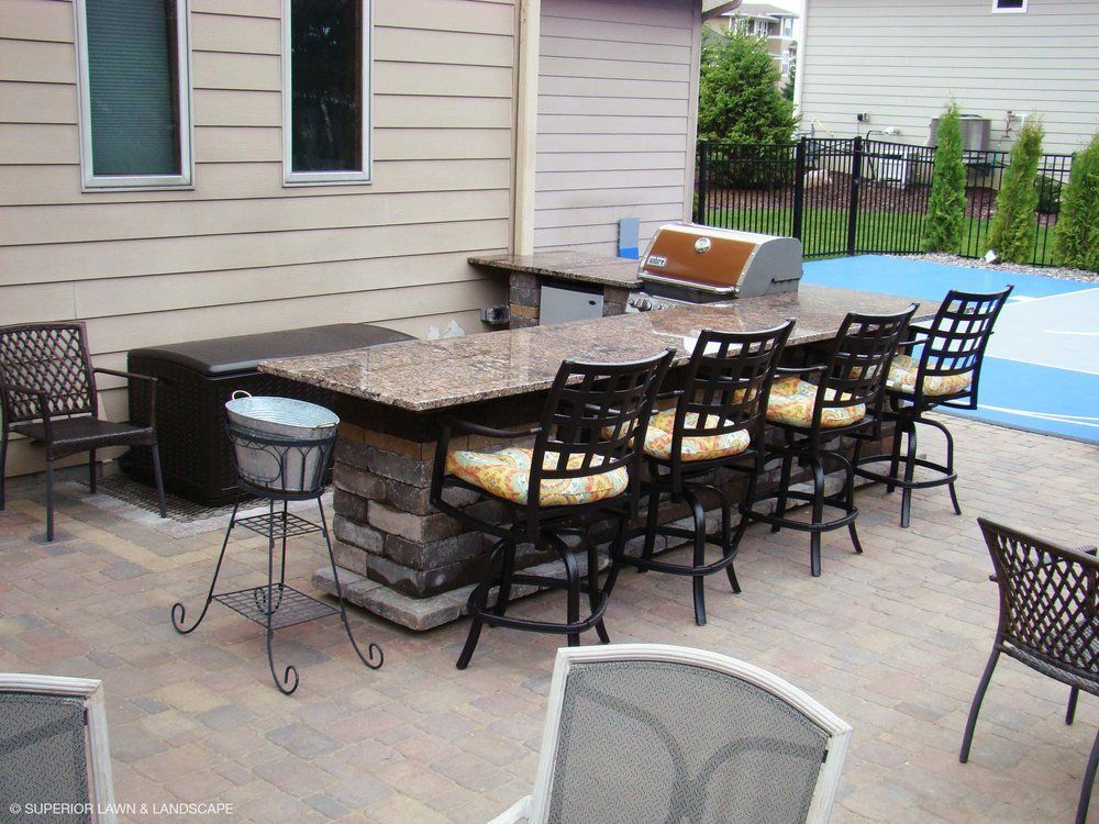 A patio with a table and chairs and a grill
