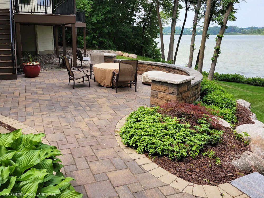 A patio with a table and chairs overlooking a lake.