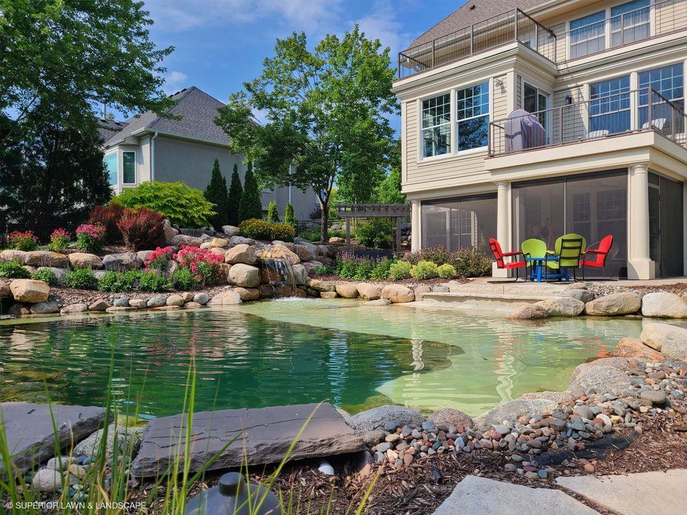 A large house with a screened in porch and a pond in front of it.