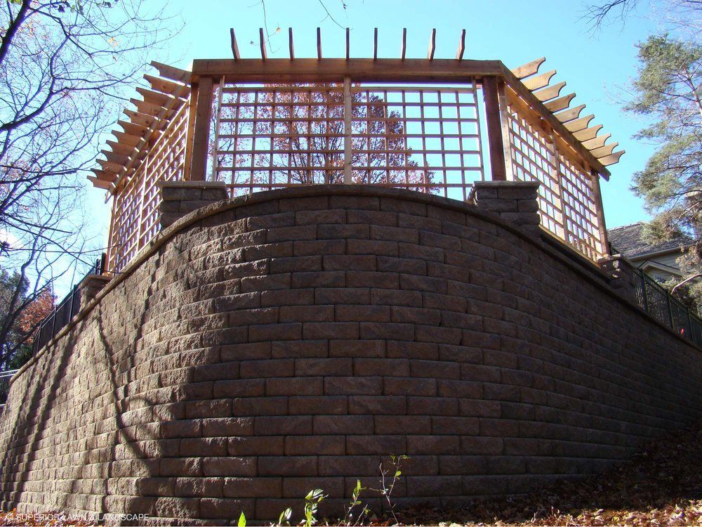 A brick wall with a pergola on top of it