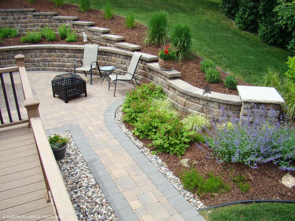 A patio with a brick wall and chairs and a fire pit