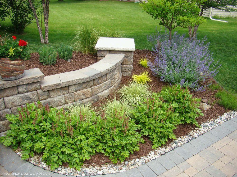 A brick wall is surrounded by plants and flowers in a garden.