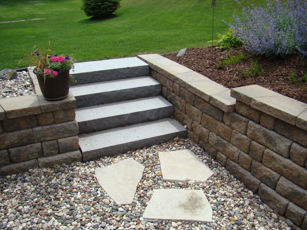 A set of stairs leading up to a stone wall surrounded by gravel.
