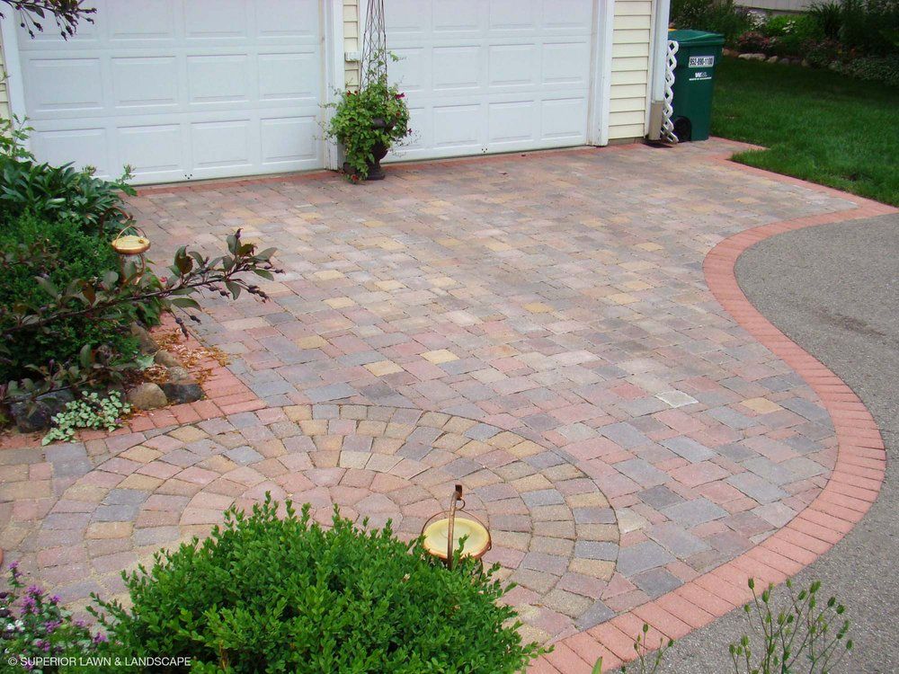 A brick driveway with a circular design in front of a garage door